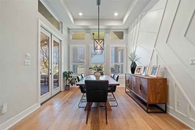 dining area featuring baseboards, light wood-style flooring, a tray ceiling, french doors, and recessed lighting