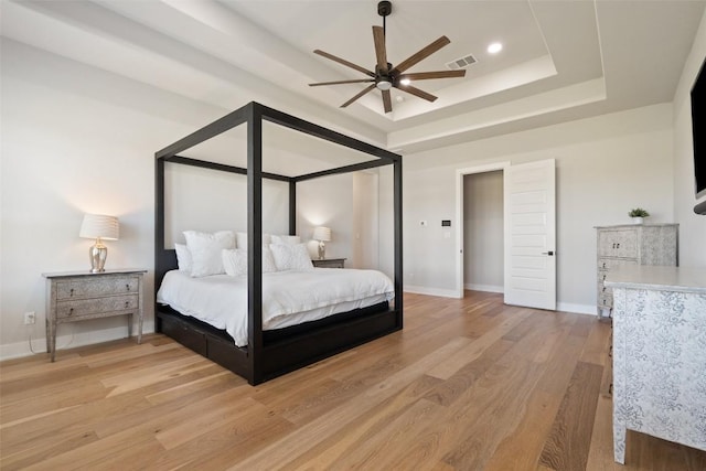 bedroom with light wood-style flooring, recessed lighting, visible vents, baseboards, and a raised ceiling