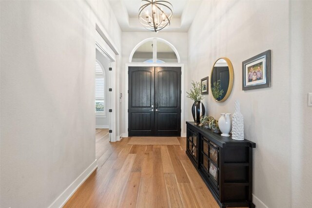 entryway featuring light wood finished floors, baseboards, and a notable chandelier