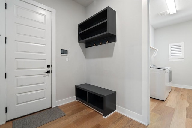 mudroom with light wood-style floors, washing machine and dryer, and baseboards