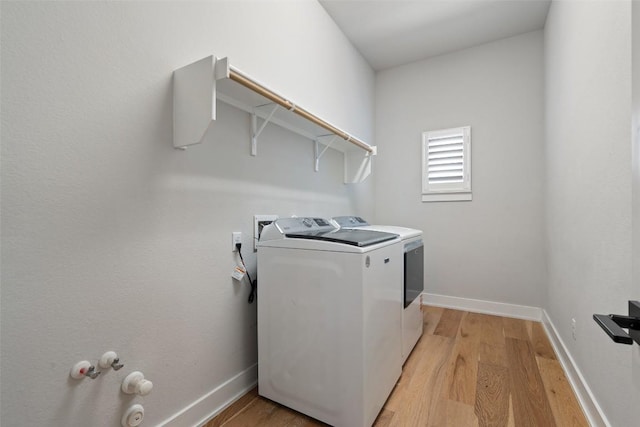 laundry area featuring laundry area, washing machine and clothes dryer, light wood-style flooring, and baseboards