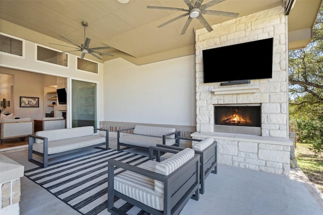 view of patio / terrace with a ceiling fan and an outdoor living space with a fireplace