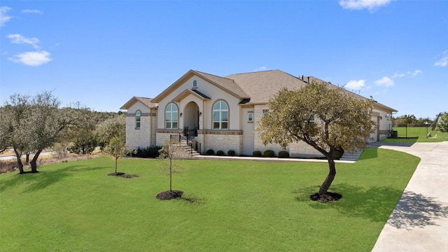 view of front of home with stucco siding, an attached garage, stone siding, driveway, and a front lawn