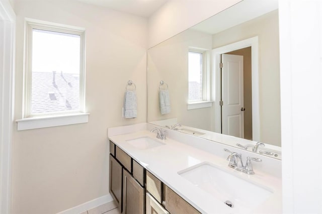 full bath featuring a sink, baseboards, and double vanity