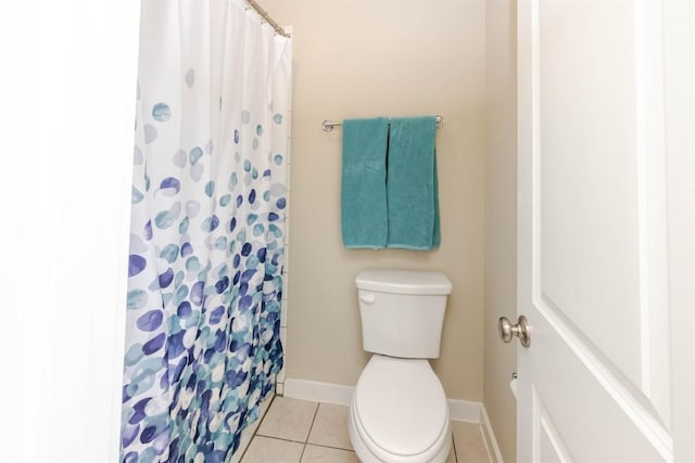 full bathroom featuring a shower with shower curtain, toilet, baseboards, and tile patterned floors