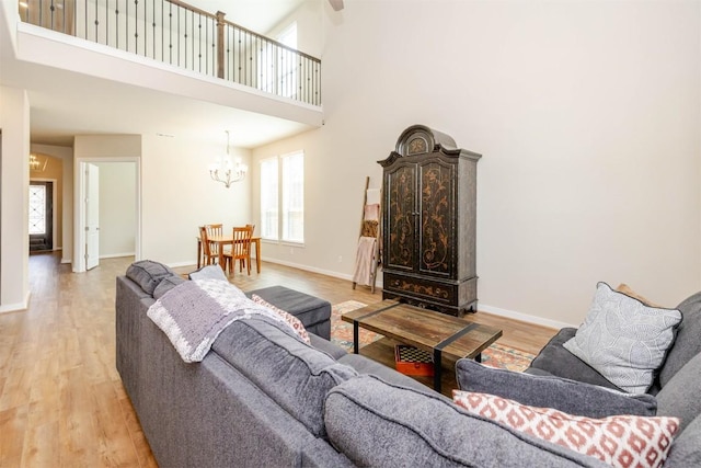 living room featuring light wood finished floors, baseboards, and an inviting chandelier