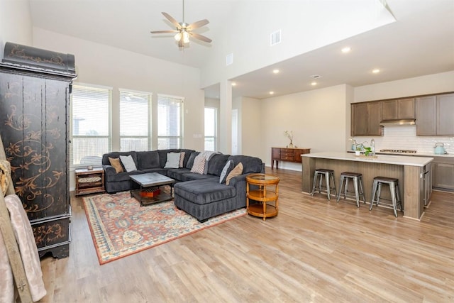 living area with visible vents, a ceiling fan, light wood-style floors, high vaulted ceiling, and recessed lighting