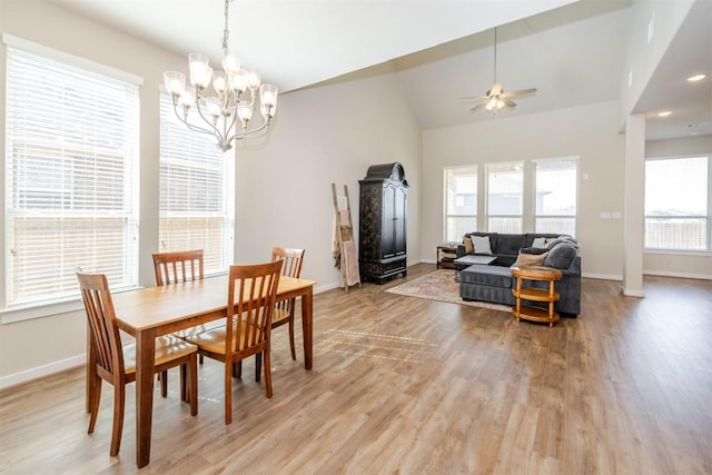 dining area with light wood-type flooring, lofted ceiling, baseboards, and ceiling fan with notable chandelier