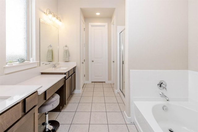 bathroom featuring tile patterned flooring, vanity, baseboards, a bath, and a stall shower