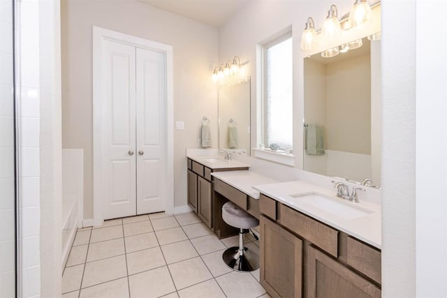 bathroom featuring a tub, tile patterned flooring, two vanities, and a sink