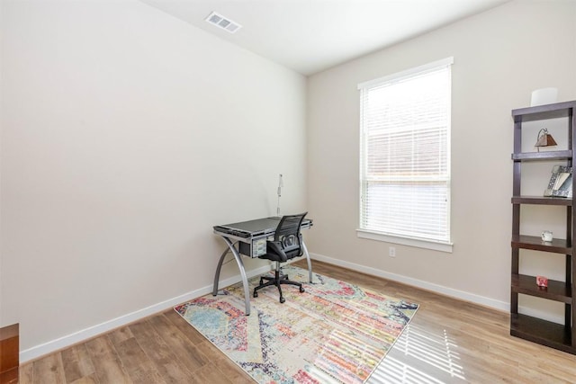 office area with a healthy amount of sunlight, baseboards, visible vents, and wood finished floors