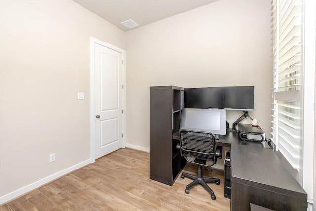 office space with light wood-style floors, visible vents, and baseboards