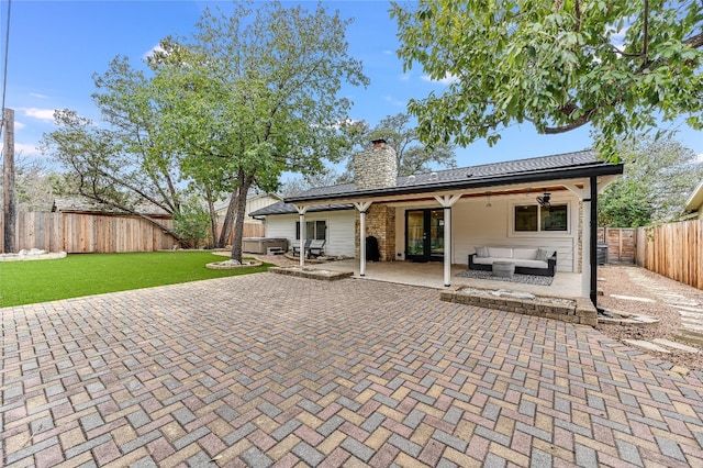 rear view of property featuring a lawn, an outdoor living space, a fenced backyard, a chimney, and a patio area