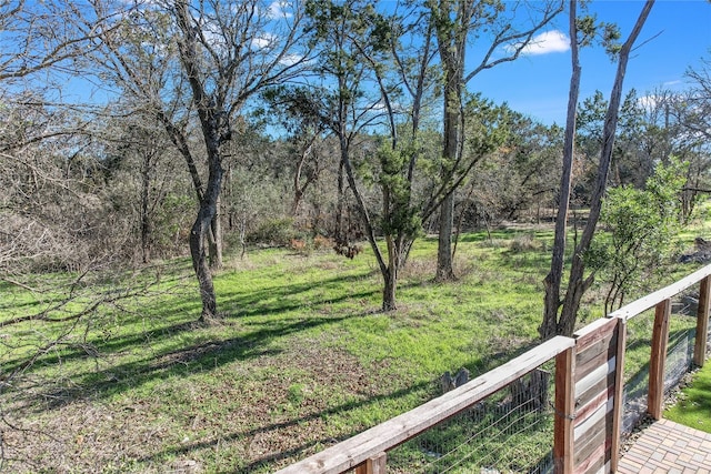 view of yard with a wooded view and fence