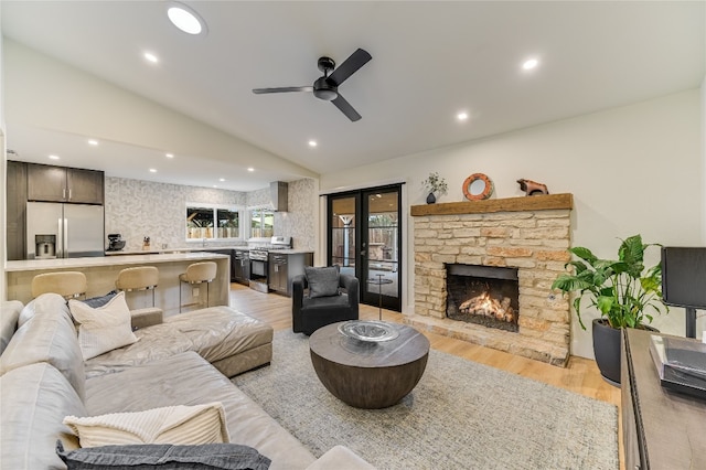 living room featuring ceiling fan, light wood-type flooring, lofted ceiling, recessed lighting, and a fireplace