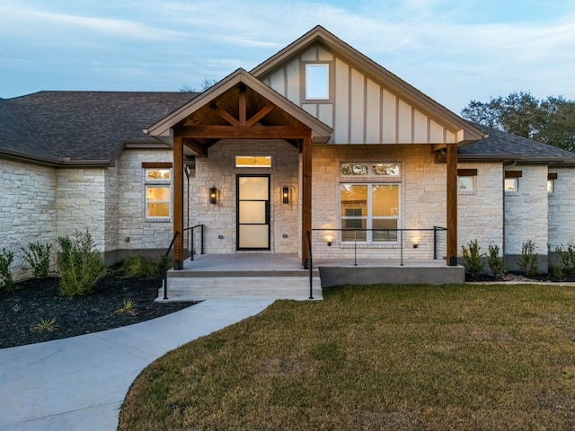 view of front of house with board and batten siding, a shingled roof, a front lawn, and a porch