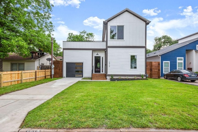 view of front of house with an attached garage, fence, driveway, a front lawn, and board and batten siding