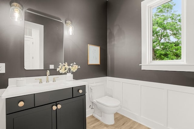 1912 Madison Ave, Austin, TX 78757 - bathroom featuring wainscoting, toilet, vanity, wood finished floors, and a decorative wall