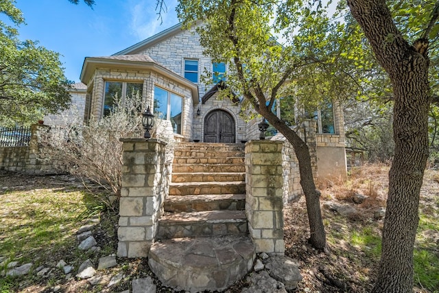 view of front facade with stone siding and fence