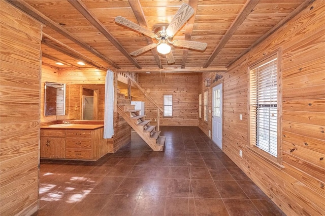 interior space featuring a ceiling fan, wood ceiling, a sink, wooden walls, and stairs