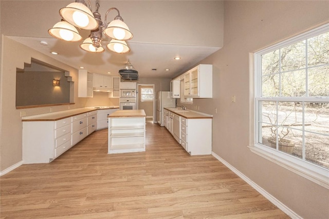 kitchen featuring light wood-style floors, white appliances, a sink, and baseboards