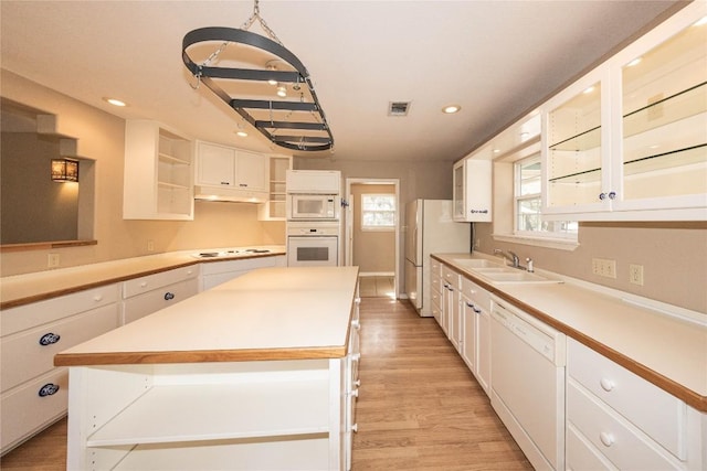 kitchen with white appliances, visible vents, a center island, open shelves, and a sink