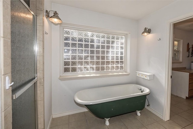 bathroom with a freestanding bath, a stall shower, tile patterned flooring, and baseboards