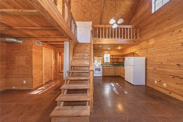 stairway featuring visible vents, wood walls, a towering ceiling, and tile patterned floors