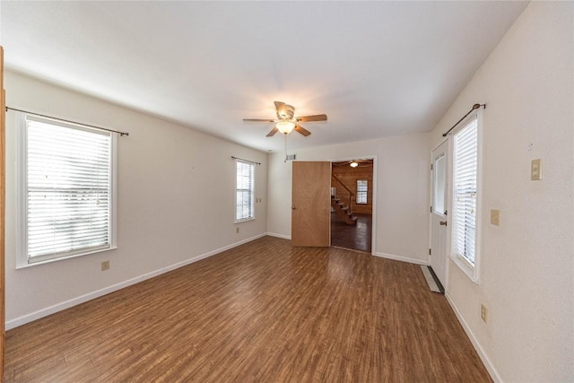 unfurnished living room with stairs, ceiling fan, wood finished floors, and baseboards