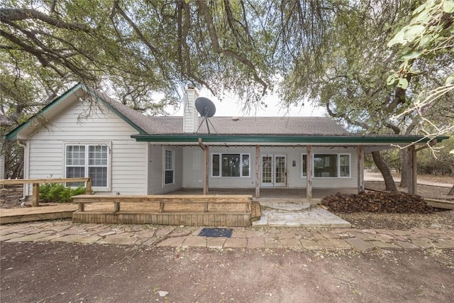 view of front of property featuring french doors, a chimney, a patio area, and a wooden deck