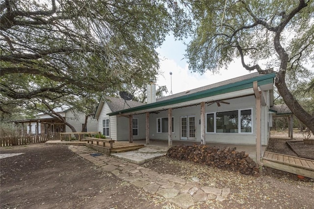 rear view of house with a ceiling fan, french doors, a chimney, and a wooden deck