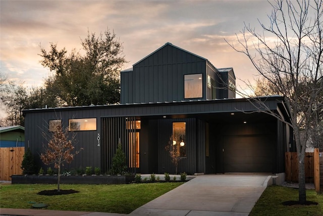 view of front of home with board and batten siding, fence, a garage, driveway, and a front lawn