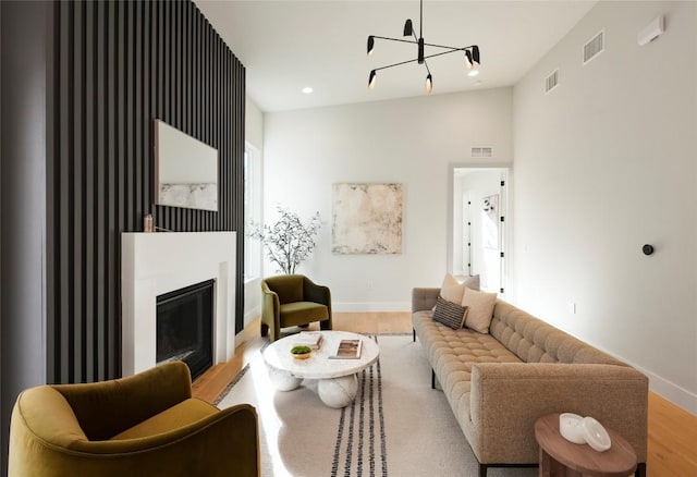 living room with a glass covered fireplace, visible vents, baseboards, and wood finished floors