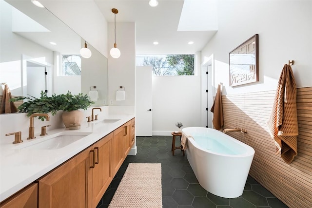 bathroom with double vanity, a freestanding tub, tile patterned flooring, and a sink