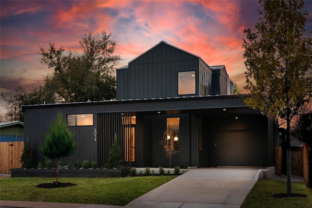 view of front of property with a lawn, board and batten siding, fence, and concrete driveway