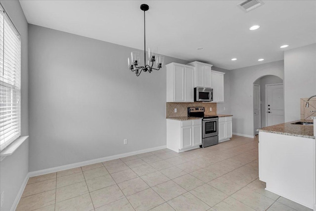 kitchen featuring a wealth of natural light, visible vents, stainless steel appliances, and arched walkways