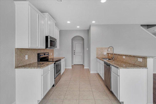 kitchen featuring appliances with stainless steel finishes, a sink, white cabinetry, and light stone countertops