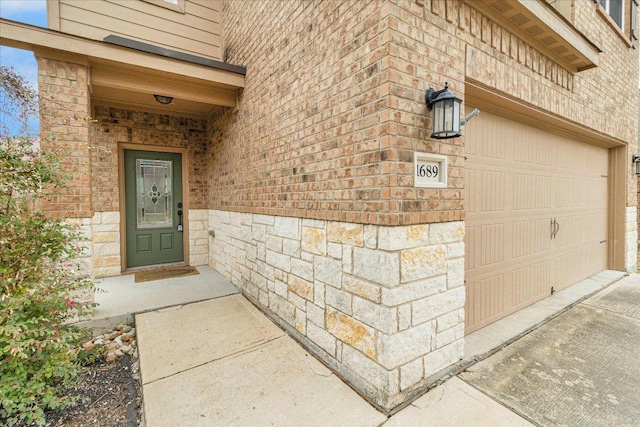 property entrance featuring a garage, stone siding, and brick siding