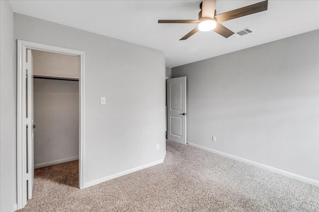 unfurnished bedroom featuring a closet, carpet flooring, a walk in closet, and baseboards