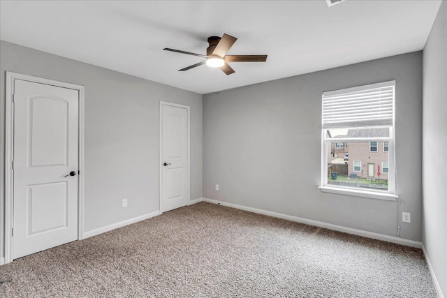 spare room featuring carpet, baseboards, and ceiling fan