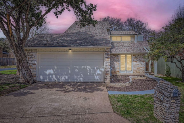 view of front of home with a garage, concrete driveway, a shingled roof, and stone siding