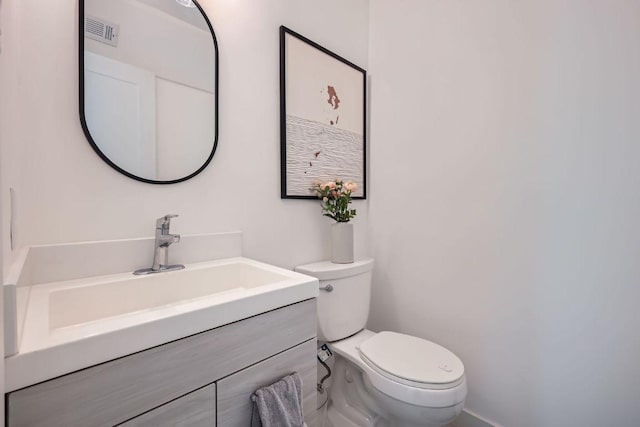 half bathroom featuring toilet, vanity, and visible vents