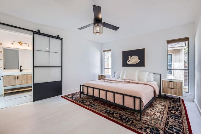 bedroom featuring ensuite bathroom, ceiling fan, light wood-type flooring, and baseboards