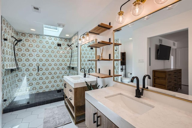 bathroom featuring a shower stall, visible vents, two vanities, and a sink