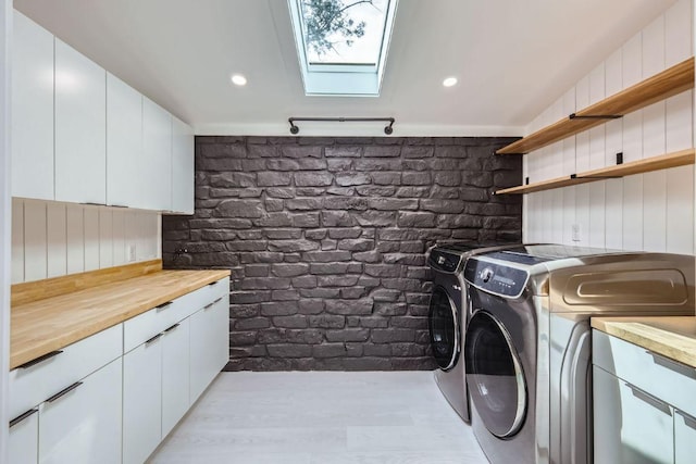 laundry area with light wood-type flooring, a skylight, recessed lighting, and separate washer and dryer