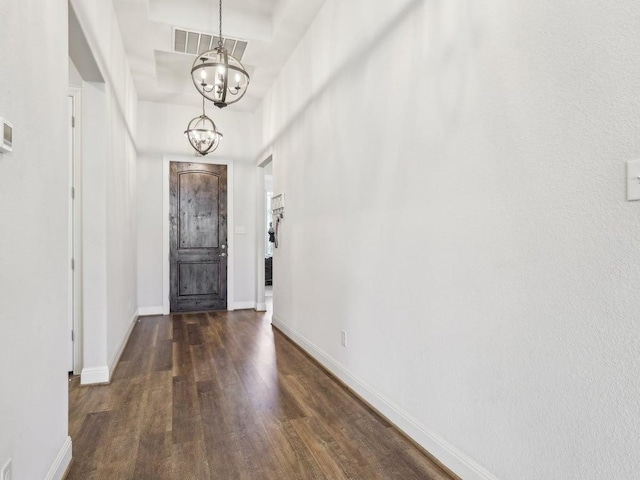 foyer entrance with an inviting chandelier, baseboards, visible vents, and wood finished floors