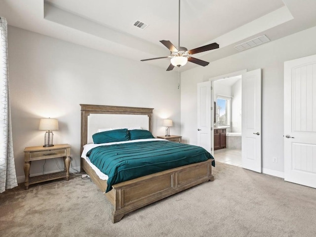 141 Bear Paw Run, Georgetown, TX 78628 - carpeted bedroom featuring a raised ceiling, ensuite bathroom, baseboards, and a ceiling fan