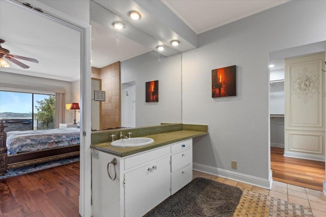 ensuite bathroom featuring baseboards, a ceiling fan, connected bathroom, wood finished floors, and vanity