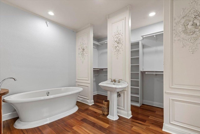 full bath featuring a freestanding tub, a spacious closet, and wood finished floors