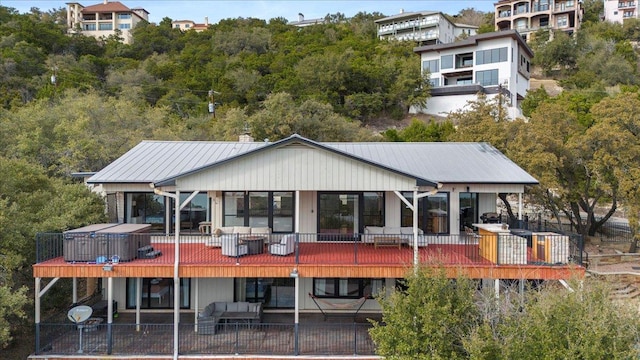 rear view of house featuring a patio area, a deck, metal roof, and a standing seam roof